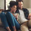 a couple sitting on a couch looking at a phone