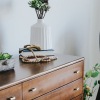 a dresser with a vase of plants on top